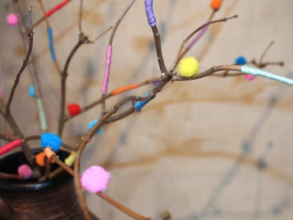 Äste mit Bändern und Pompons verzieren